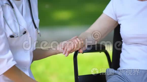 室外轮椅残疾老年妇女的女性治疗师手牵手
