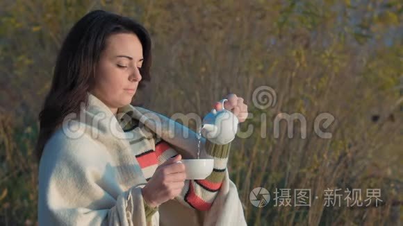 慢动作美丽的女人在河边的瓷茶壶浇绿茶