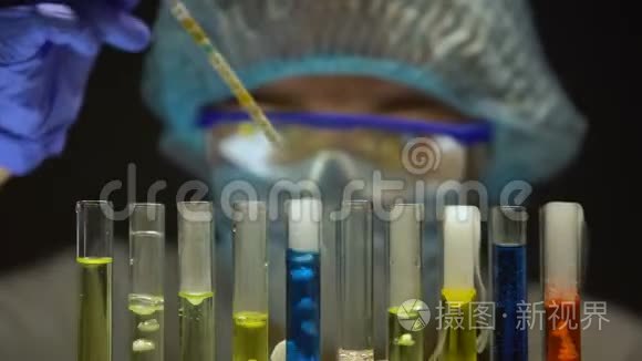 在黑暗实验室用蓝色液体测量试管中酸度水平的科学家