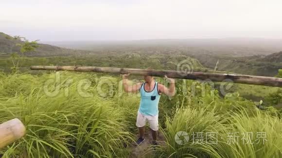 运动员举起沉重的木棒在热带山和高地景观。 健美运动员训练新闻练习