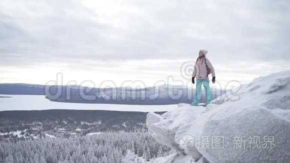 迷人的女人正张开双臂站在雪山的边界上
