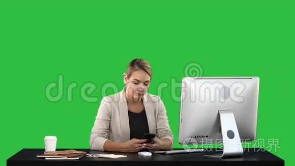 漂亮的女商人坐在办公桌前的绿色屏幕上发短信，Chroma键。