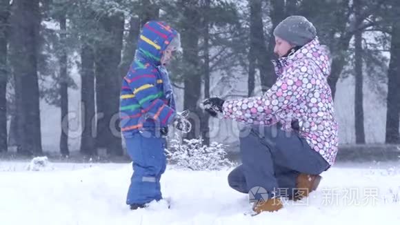 妈妈在一片冬林的手里给孩子递了一个雪球..