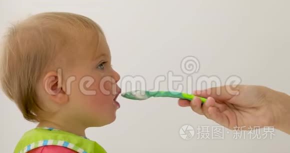 可爱的孩子用绿色勺子喂养视频