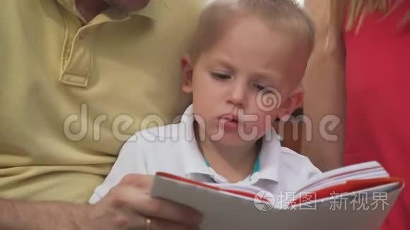一个小男孩和他的父母一起仪式一本书。 特写