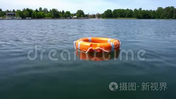橙色的救生圈漂浮在远离海岸的湖水上。 万向节运动