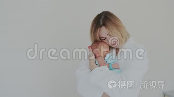 快乐的母亲拥抱她新生的婴儿，抚摸他的手。 宝宝和妈妈在一起.. 生育观念。 养育子女