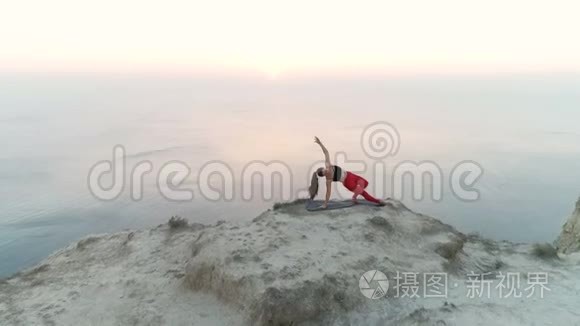 美丽的女人正在做瑜伽，Vasisthasana，山顶的侧帆船，日落时的海景。