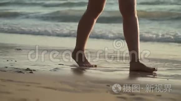 日落时分在海滩上散步的女人的双腿特写