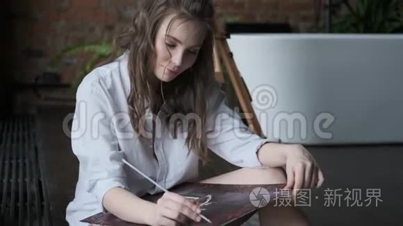 一位迷人的女画家在轻松的气氛中工作的肖像。 艺术家在家里的工作室里画了一幅画