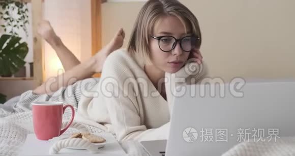 女人用笔记本电脑，在床上吃饼干