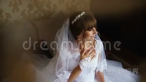 美丽的新娘摆在窗边，手捧花束。 新娘`早上。