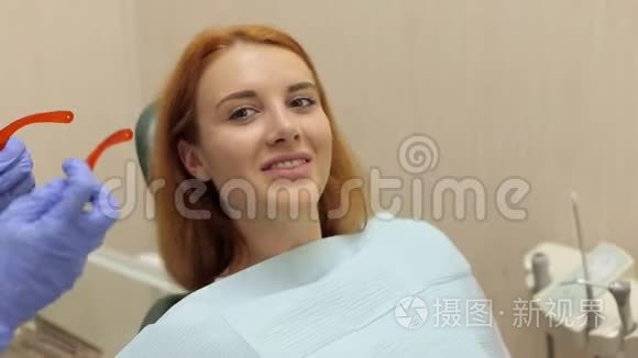 一位女牙医在病人身上戴上防护橙色`眼镜。