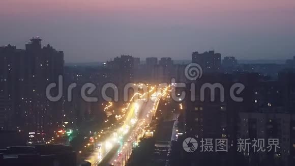 夜晚的城市在阴霾中，全景的城市与高速公路，汽车走与前灯。