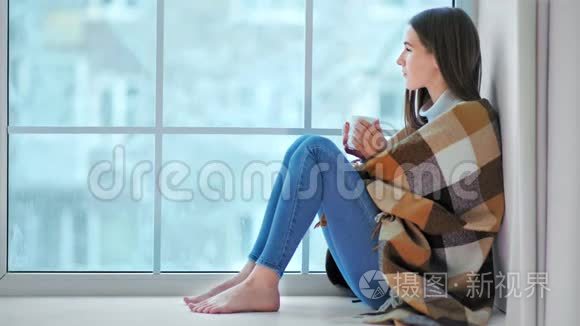 光着脚微笑的女人坐在窗台上看冬天的天气