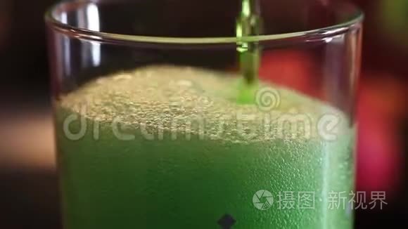 放大绿色雌龙饮料倒入水玻璃与大量气泡和泡沫。