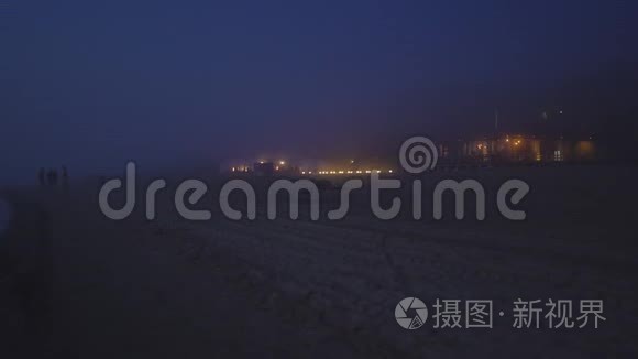 令人惊叹的黑暗风景，薄雾，罕见的幽灵之夜，日落后，人们的轮廓和房子与黄色钨灯在。