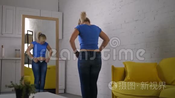 焦急的女人努力扣牛仔裤视频