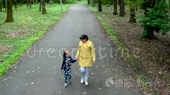 一位美丽的母亲和她可爱的小女儿在公园里散步。