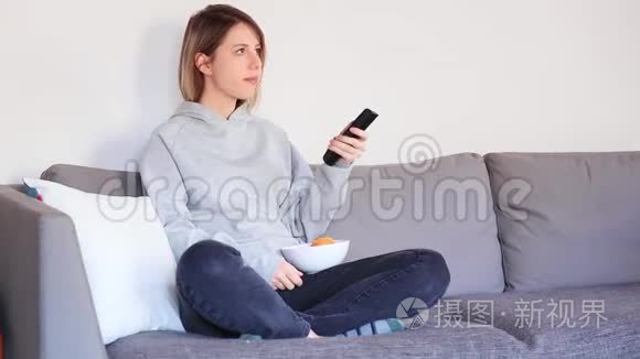 年轻女子拿着遥控器看电视视频
