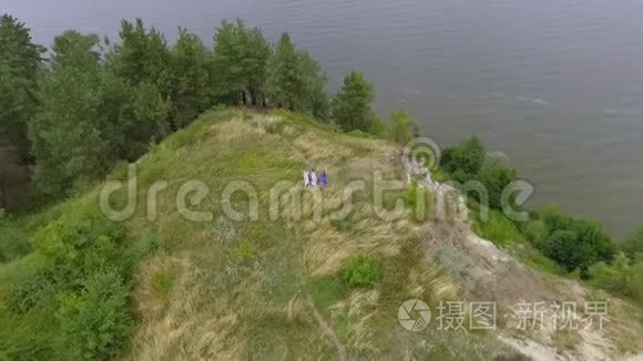 在欢乐的女朋友的空中观看，她们穿着夏日的长时装，走在湖边或河边。 两个高加索人和一个