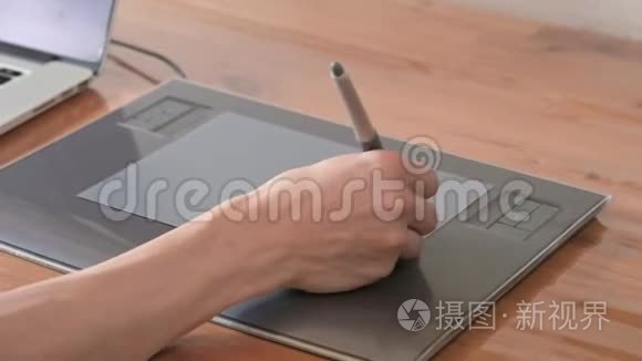 一位男性设计师的特写镜头借助他的笔记本电脑。 平板电脑和笔笔