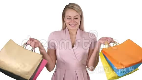 兴奋的漂亮年轻女士站着看相机，在白色背景上展示购物袋。
