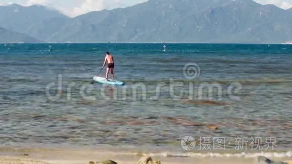 盖伊在海边靠山的沙滩上冲浪视频