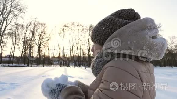 少女在冬天的公园里把白雪抛起来微笑。 圣诞节。 在寒冷的日子里举行雪的运动会