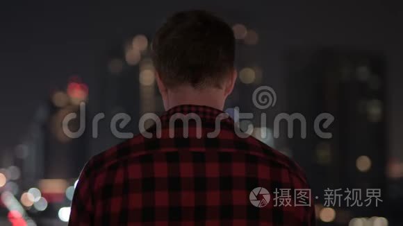 年轻的嬉皮士看城市夜景的后景视频