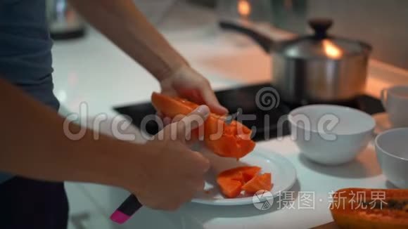 一名年轻人在厨房用新鲜的热带水果为家人准备早餐时慢镜头