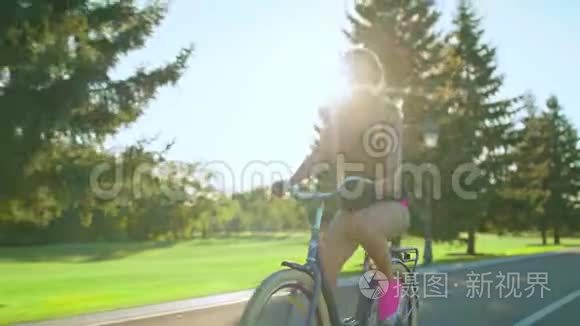 疲惫的骑自行车的女人在夏天的公园里骑自行车时，从脸上擦汗