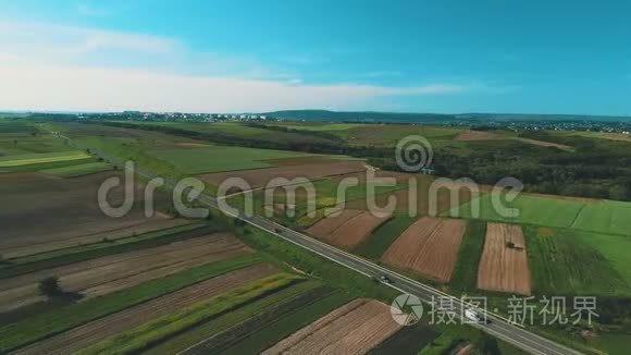 从空中俯瞰田野之间的道路。 夏天的颜色。 绿色乡村和汽车的空中行驶。 4K.