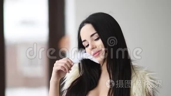 特写一幅美丽的女人的肖像，在她的脸附近玩羽毛