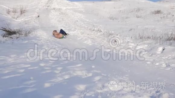 冬天，快乐的女孩从雪山上滚过白雪，微笑着。 慢动作。