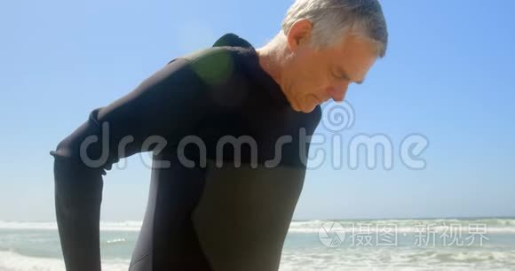 海滩上穿着湿衣服的活跃的高加索男性冲浪者的侧视图4k