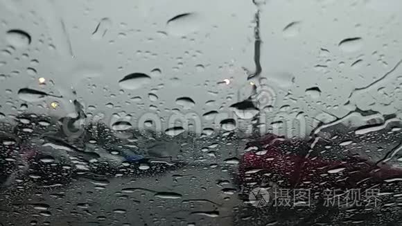 雨滴沿着挡风玻璃流下。 从车里看。 街上跑着一个湿漉漉的人。