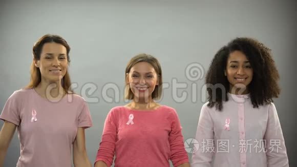 微笑的女人用粉红色的丝带举起双手，对抗乳腺癌