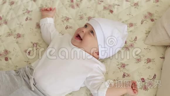 一个刚出生的可爱男孩戴着白色帽子躺在家里的床上。