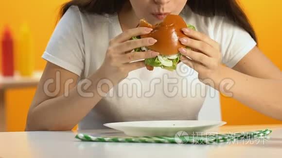 女性在快餐店吃高脂肪的汉堡，食欲旺盛，饮食肥胖