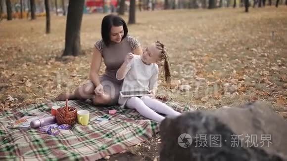 妈妈教女儿用粉笔在黑板上写字母，字母表。 一位年轻的母亲玩得很开心