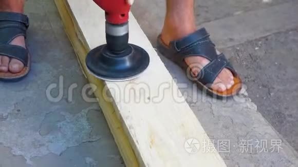 一个人用钻头上的喷嘴擦板. 用砂纸打磨木质木材..