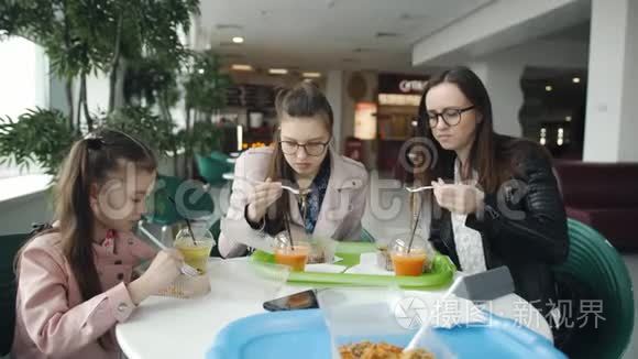 一家人一起在咖啡馆吃午饭。 母亲和两个女儿在咖啡馆里吃面条，喝新鲜果汁。