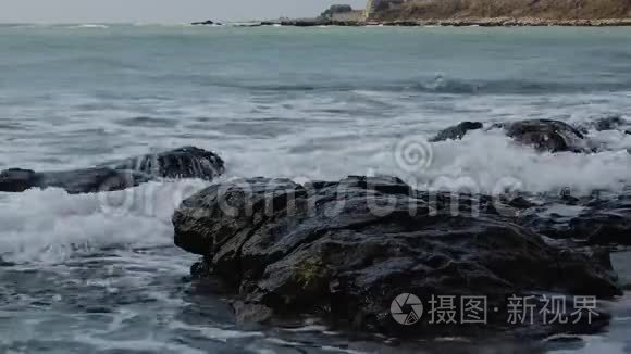 海上的风暴，海岸上的波浪破碎，海水的飞溅和岩石下的水的泡沫。 保加利亚黑海