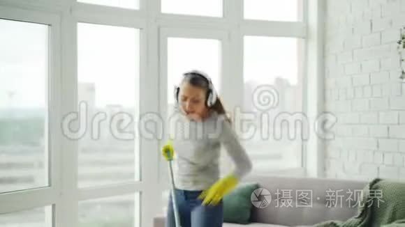 快乐的年轻金发女郎正在做家务，在现代的房子里玩得很开心，她正在用拖把、唱歌和跳舞洗地板。