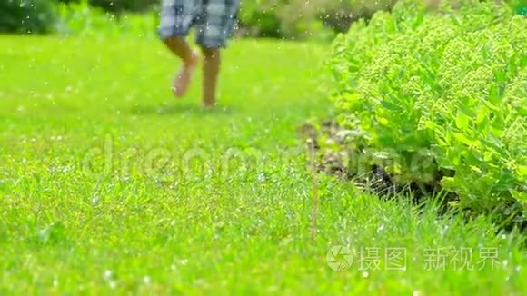 赤脚男孩跑在新鲜的绿草慢动作。孩子玩得开心。夏天，大自然，快乐的童年