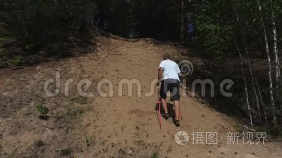 徒步旅行者用手杖和望远镜爬上小山