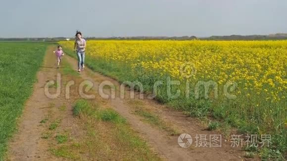 一个有孩子的女人在大自然中玩耍。 一个幸福的家庭正在新鲜的空气中奔跑。 一个带着孩子的女孩沿着一个乡村