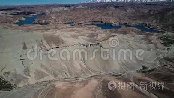 以蓝湖和白雪覆盖的山脉为背景，从空中俯瞰山谷。