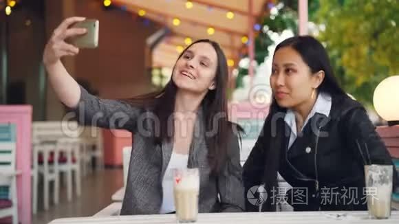 快乐的女性朋友正在用智能手机进行在线视频通话，看着屏幕，坐在街上聊天